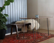 The Huron Cafe Table set against a wall with a coordinating rug and chair